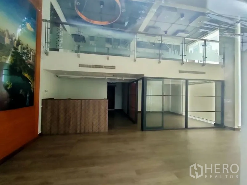 Office Space for rent in Pathum Wan, Bangkok - Loft-style office interior with mezzanine, glass railings, wood flooring, reception counter, and a glass-partitioned meeting room.