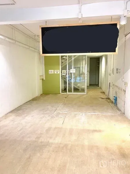 Shophouse for rent in Phaya Thai, Bangkok - Open-plan ground floor with concrete floor, white walls, and a glass partition leading to the staircase.