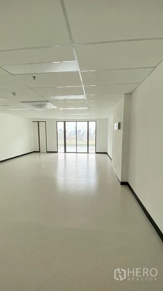 Office Space for rent in Watthana, Bangkok - Bright open-plan office interior showing ceiling panels and wide glazed doors to the view.