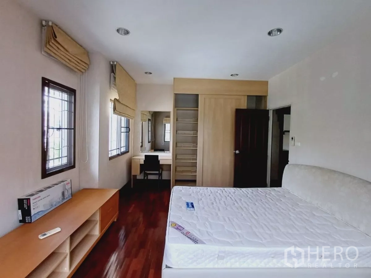 Detached House for rent or sale in Mueang Nonthaburi, Nonthaburi - Spacious bedroom with built-in wardrobe, dressing table and wood flooring.