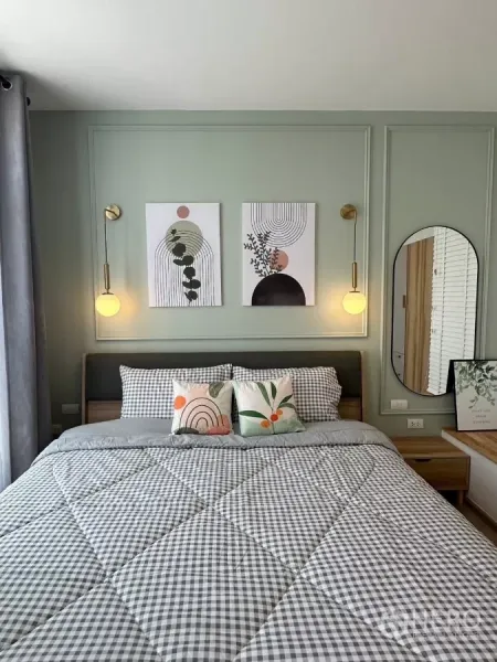 Townhouse for rent in Bang Phli, Samut Prakan - Close-up of master bed with pastel art and pendant lights on a sage green wall.