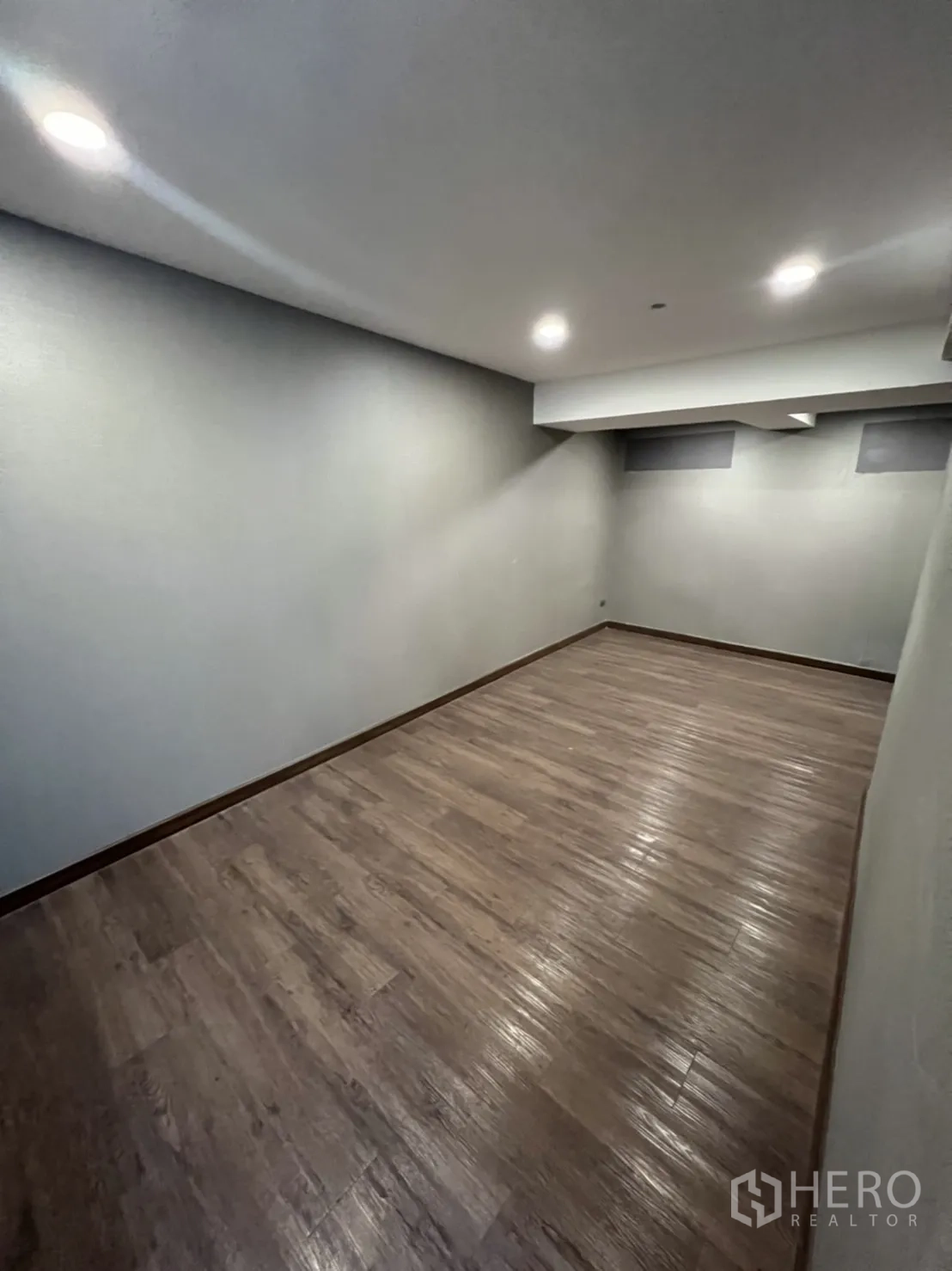 Shophouse for rent in Phra Khanong, Bangkok - Long rectangular multipurpose room with downlights and wood‑look flooring.