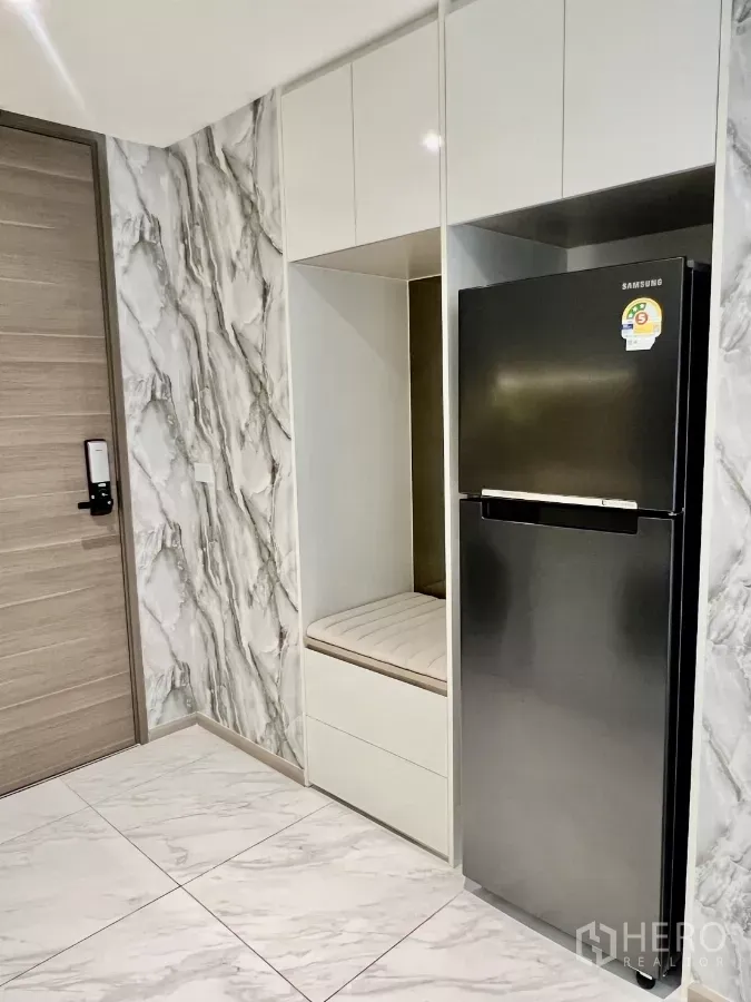 Condominium for rent in Khlong Toei, Bangkok - Entry area with marble-effect walls, built-in cabinet and stainless refrigerator in the Bangkok condo.