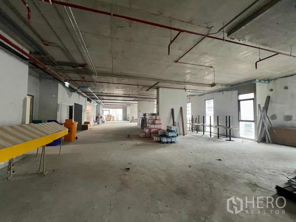 Office Space for rent in Khlong Toei, Bangkok - Long rectangular office floor plate with multiple windows and construction materials on site.