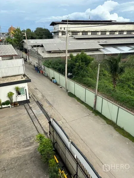Factory for sale in Ban Phaeo, Samut Sakhon - View from upper floor over quiet industrial lane outside the factory compound with perimeter wall.