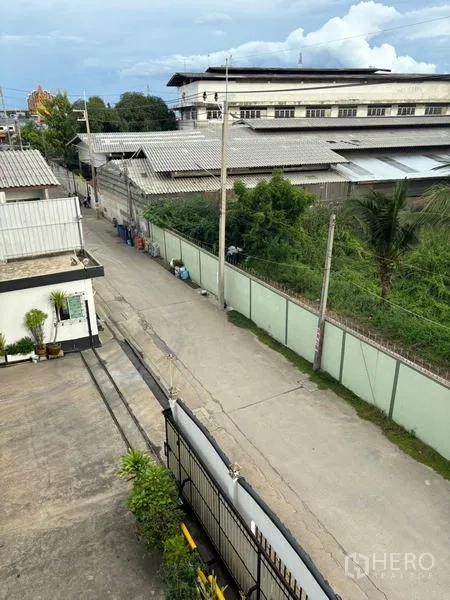 Factory for sale in Ban Phaeo, Samut Sakhon - View from upper floor over quiet industrial lane outside the factory compound with perimeter wall.