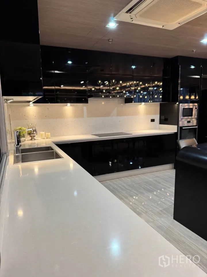 Condominium for rent or sale in Khlong Toei, Bangkok - Close-up of long white countertop and sink in a sleek modern kitchen.