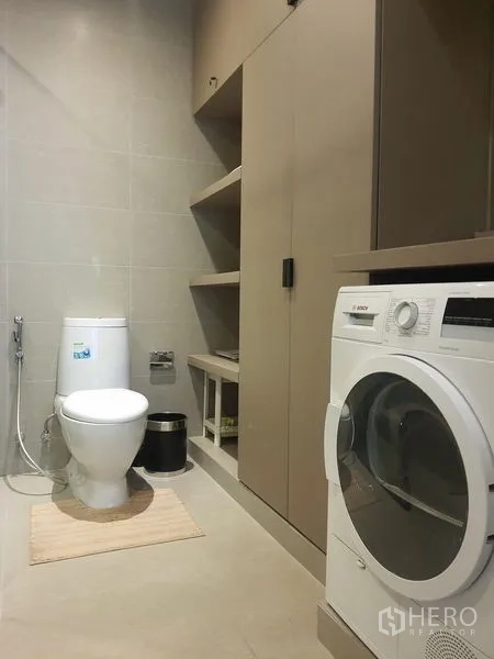Condominium for rent in Pathum Wan, Bangkok - Utility bathroom with toilet, open shelving and a front-load washing machine.