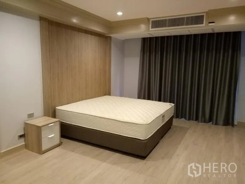 Apartment for rent in Khlong Toei, Bangkok - Second bedroom with bed, wood accent wall and full-length curtains