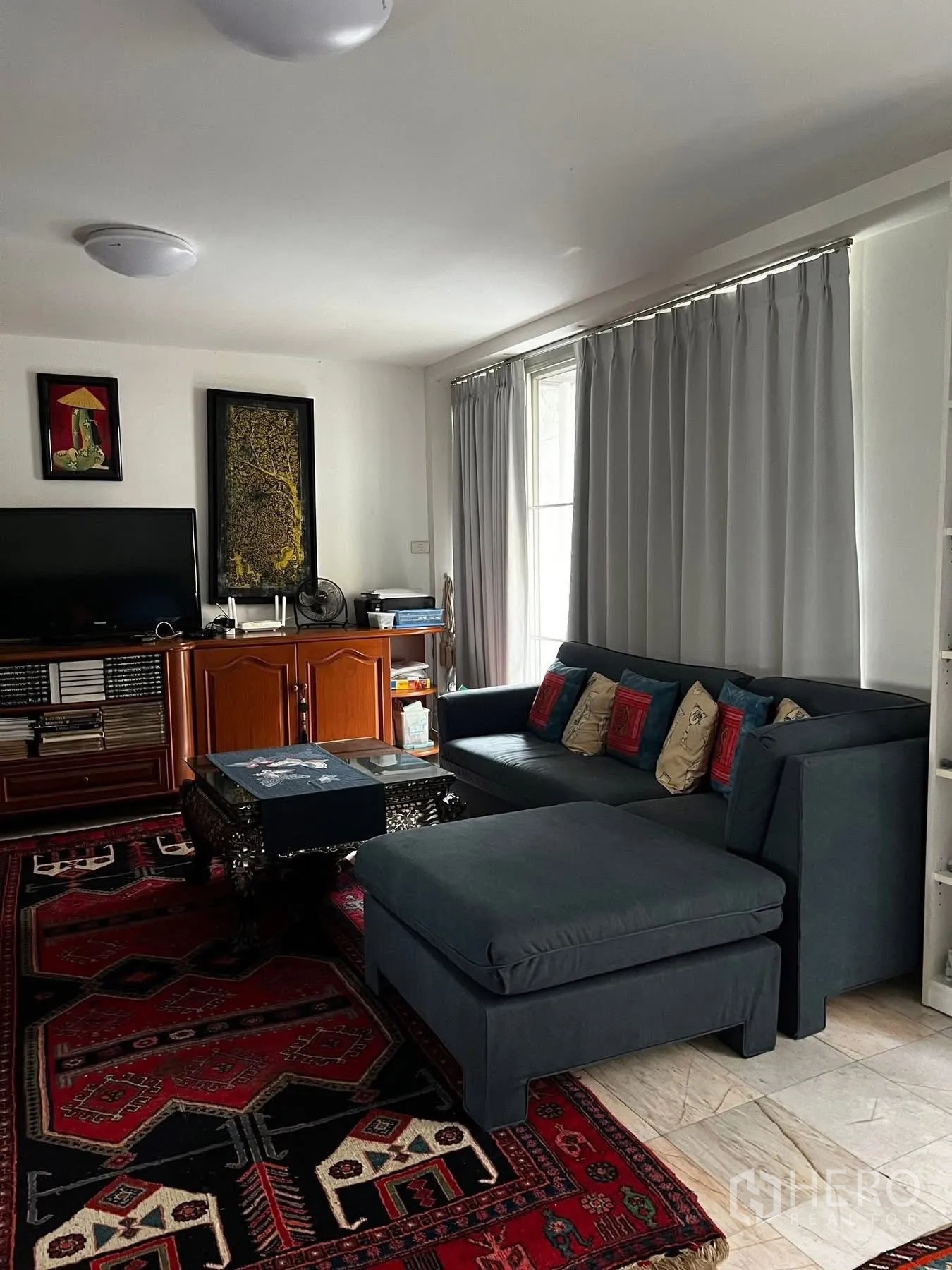 联排别墅 for rent or sale in Watthana, Bangkok - 家庭客厅配转角沙发、电视柜与落地窗帘。