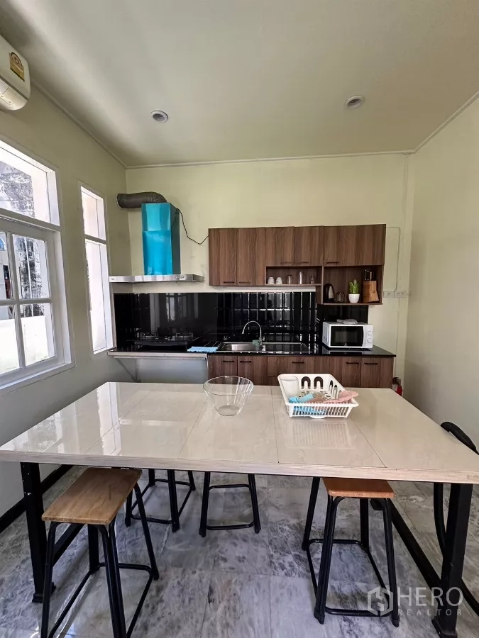 Home Office for rent in Suan Luang, Bangkok - Light-filled kitchen with breakfast island and a blue range hood.