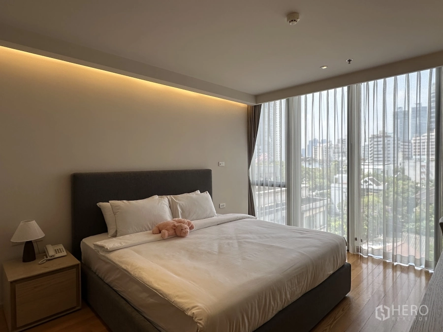 Condominium for rent in Khlong Toei, Bangkok - Bright master bedroom with floor-to-ceiling windows, city view and king bed.