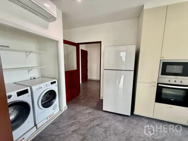 Condominium for rent - Kitchen view showing refrigerator, washer-dryer closet, and cabinetry.