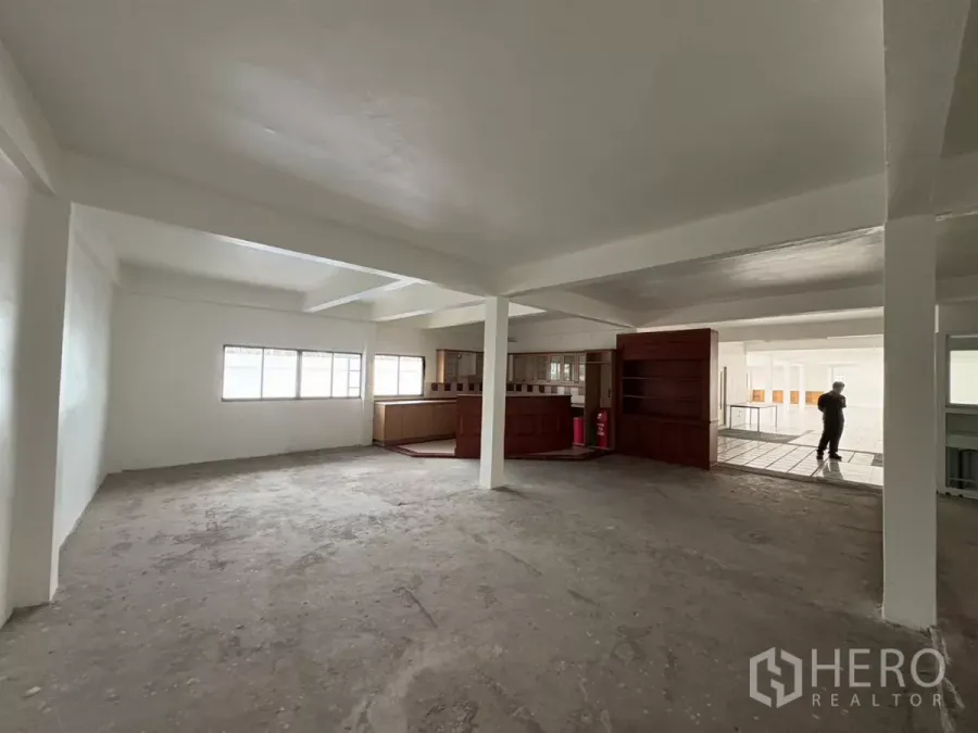 Office Space for rent in Watthana, Bangkok - Spacious unfinished office area with windows and a built-in wooden counter.