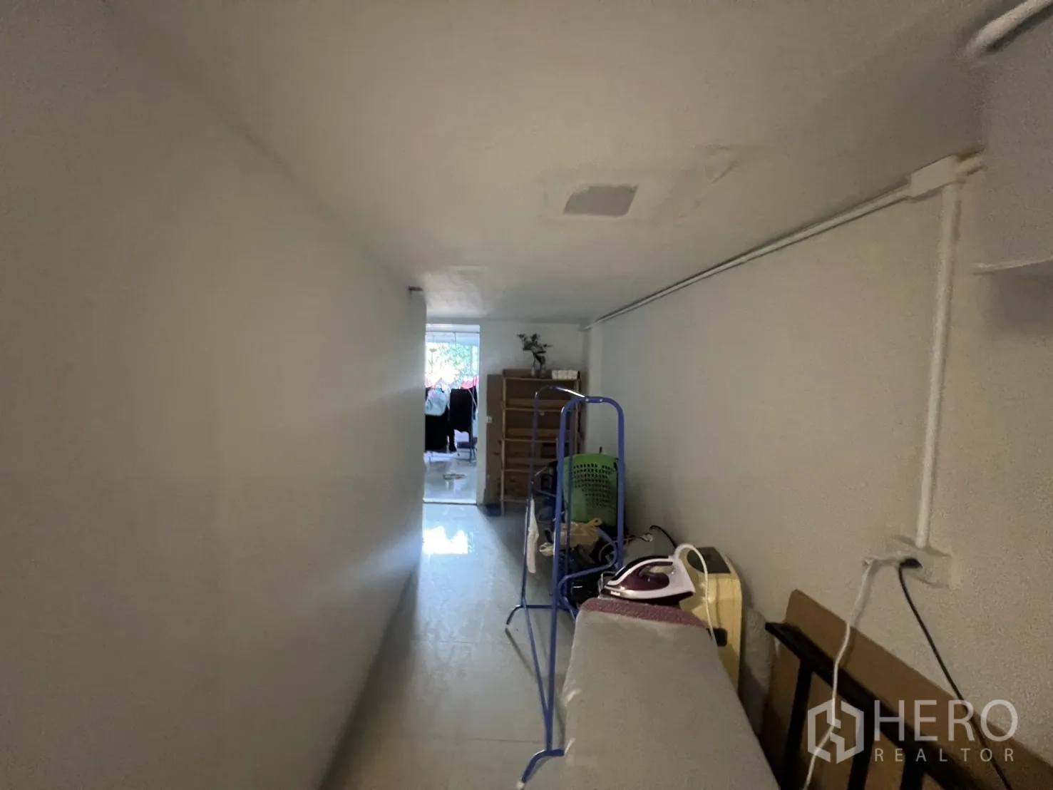 Retail Space for rent - Corridor view toward a windowed room with ironing board and storage on the side.
