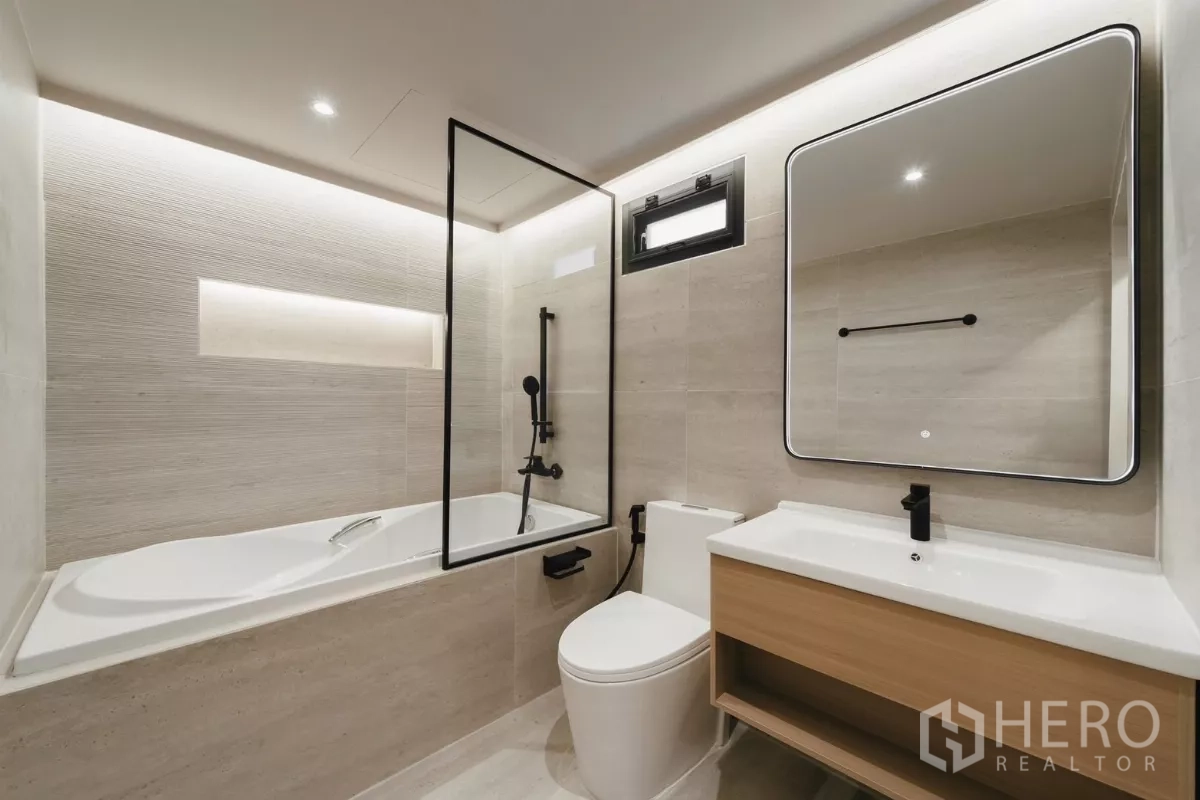 Townhouse for rent in Watthana, Bangkok - Modern bathroom with bathtub, glass screen, vanity and backlit mirror.