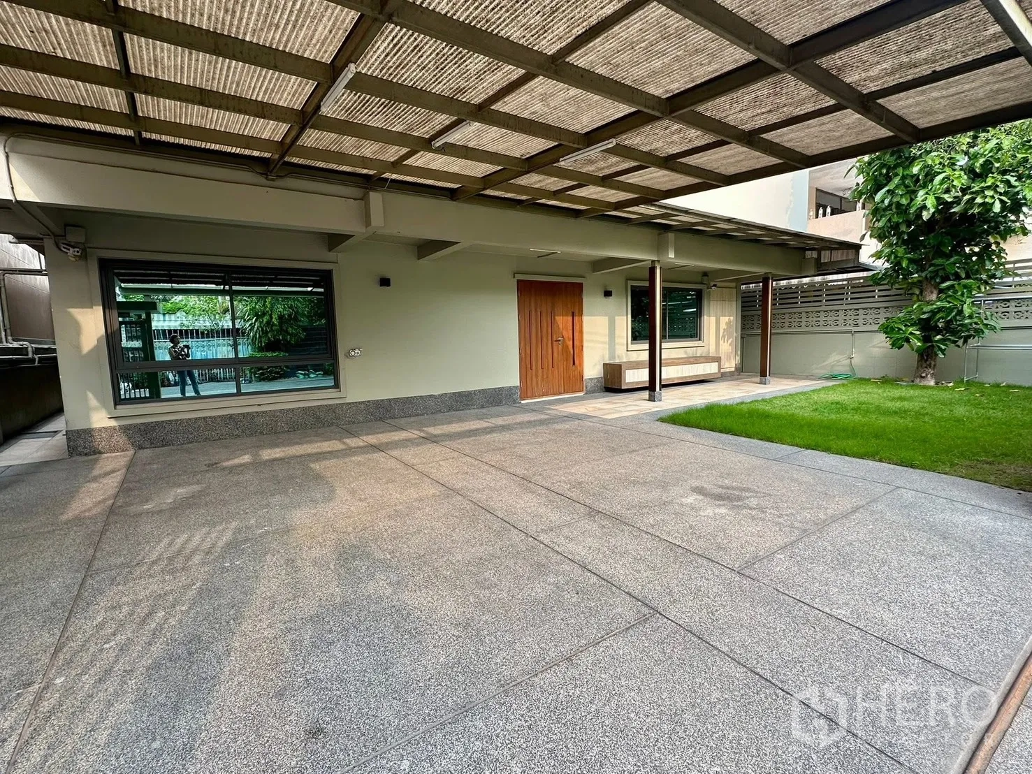 Detached House for rent in Watthana, Bangkok - Covered carport and front patio beside a small lawn and mature tree.