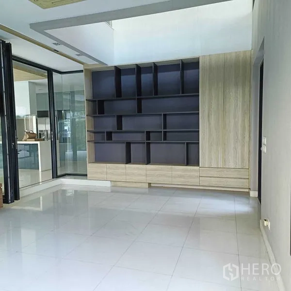 Detached House for rent or sale in Mueang Nonthaburi, Nonthaburi - Family room with custom wall shelving and folding glass doors.