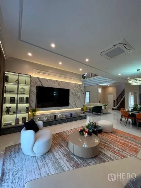 Detached House for sale in Bang Kapi, Bangkok - Living area with marble TV feature wall, display cabinets and dining beyond.