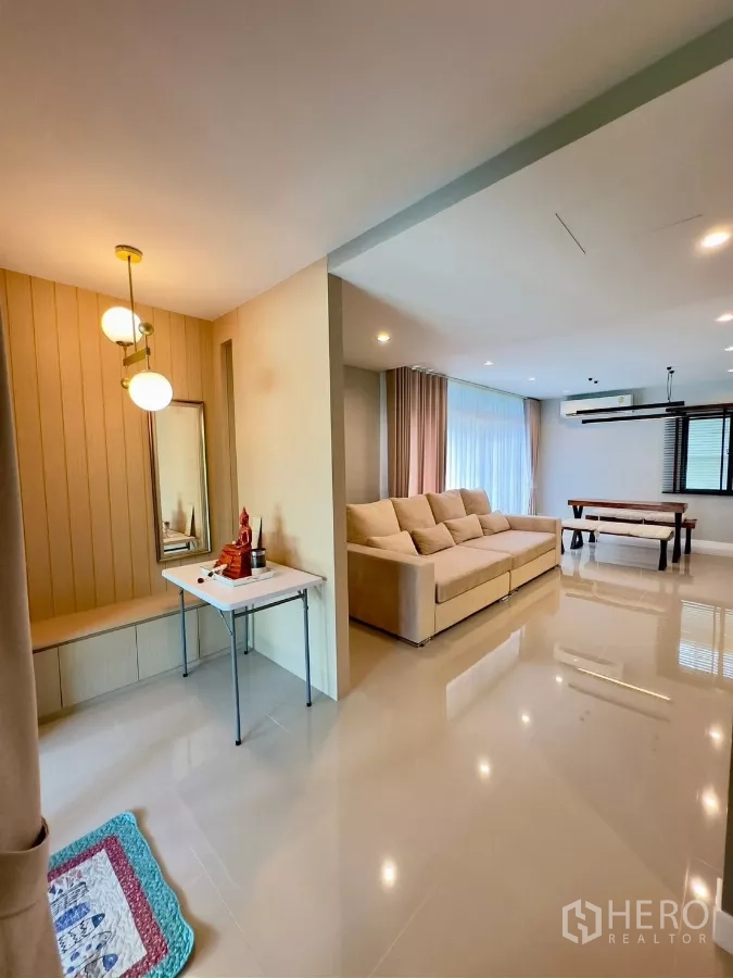 Detached House for rent in Samut Prakan - Open-plan living and dining area with large beige sofa, pendant lights and glossy floors.