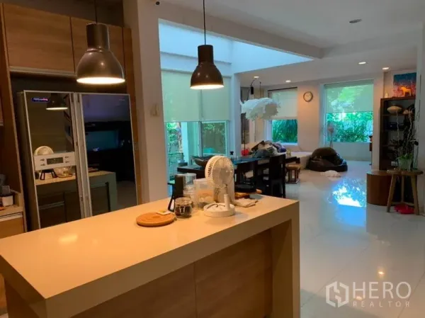 独立式住宅 出售在Suan Luang, Bangkok - 从厨房中岛望向餐客一体空间，吊灯与面向花园的大窗。