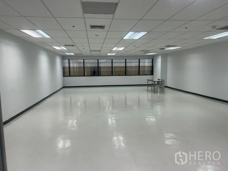 Office Space for rent in Watthana, Bangkok - Open‑plan office floor with long tinted window line and fluorescent lighting.
