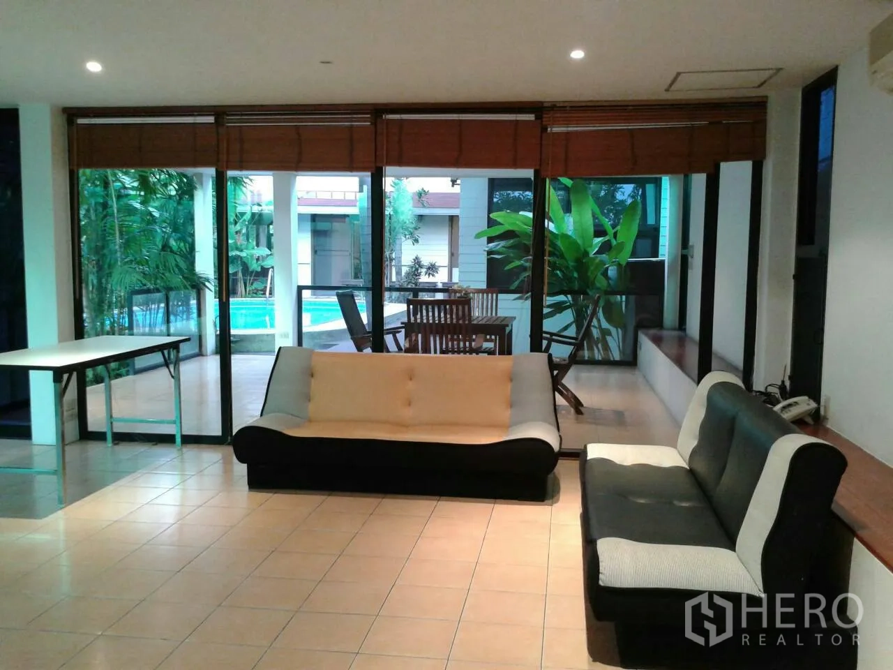 Detached House for rent in Suan Luang, Bangkok - Spacious family room with sofas opening to terrace and pool through glass walls.