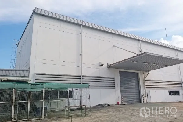 Factory for sale in Rayong - Side elevation of factory with large roller shutter and covered loading canopy.