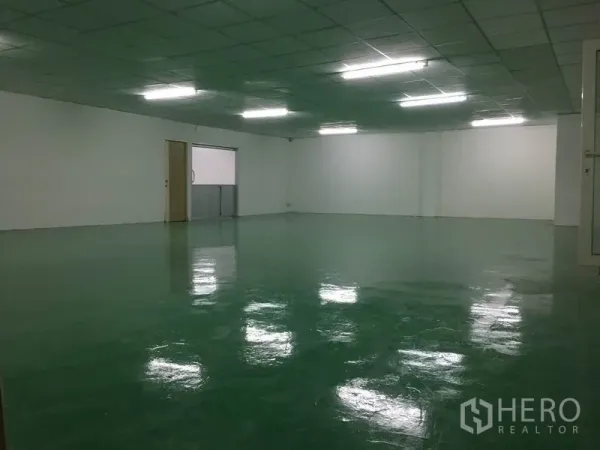 Factory for rent in Lam Luk Ka, Pathum Thani - Large production hall with green epoxy floor, white walls and suspended fluorescent lighting.