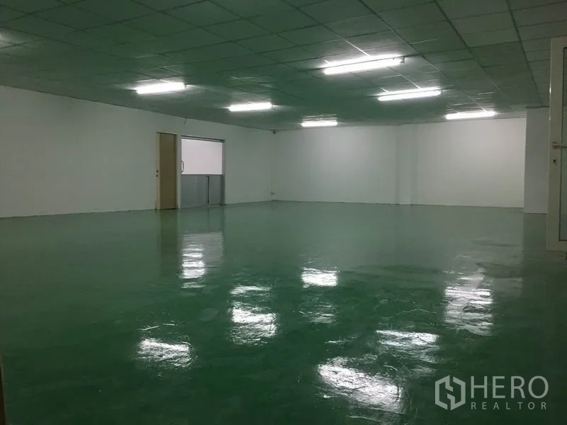 Factory for rent in Lam Luk Ka, Pathum Thani - Large production hall with green epoxy floor, white walls and suspended fluorescent lighting.