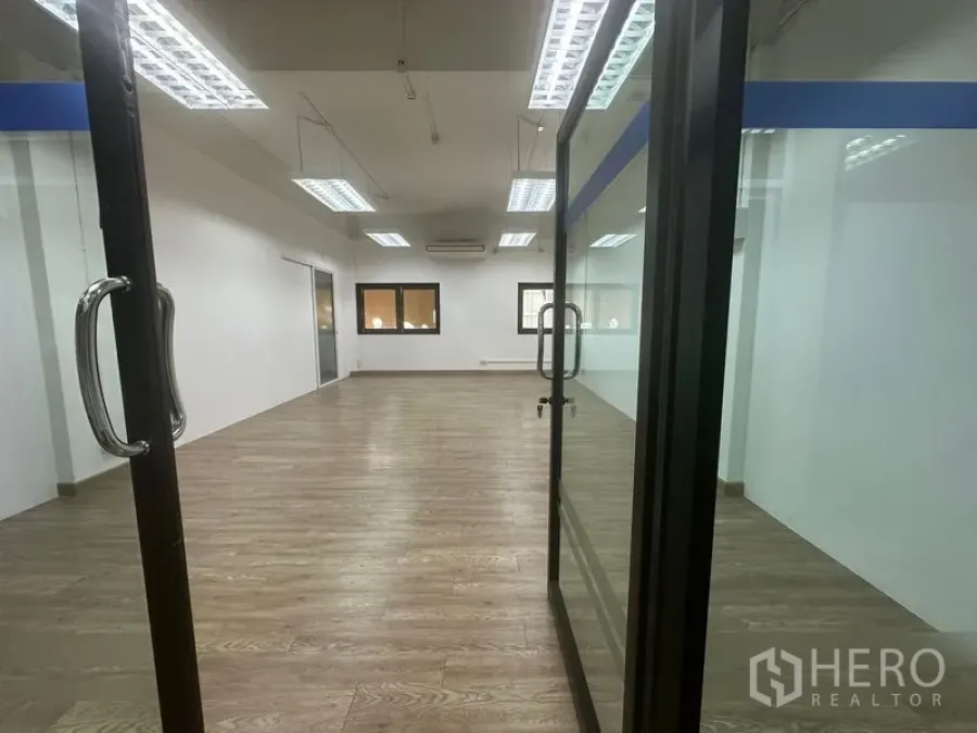 Office Space for rent in Chatuchak, Bangkok - Glass entry with stainless handles opening to an open-plan office with AC and wood floors.