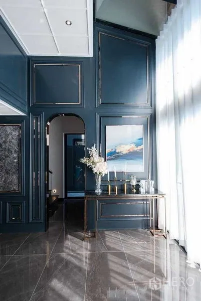Detached House for sale in Prawet, Bangkok - Entrance hall with paneled teal walls, arched doorway, console table and sheer curtains.