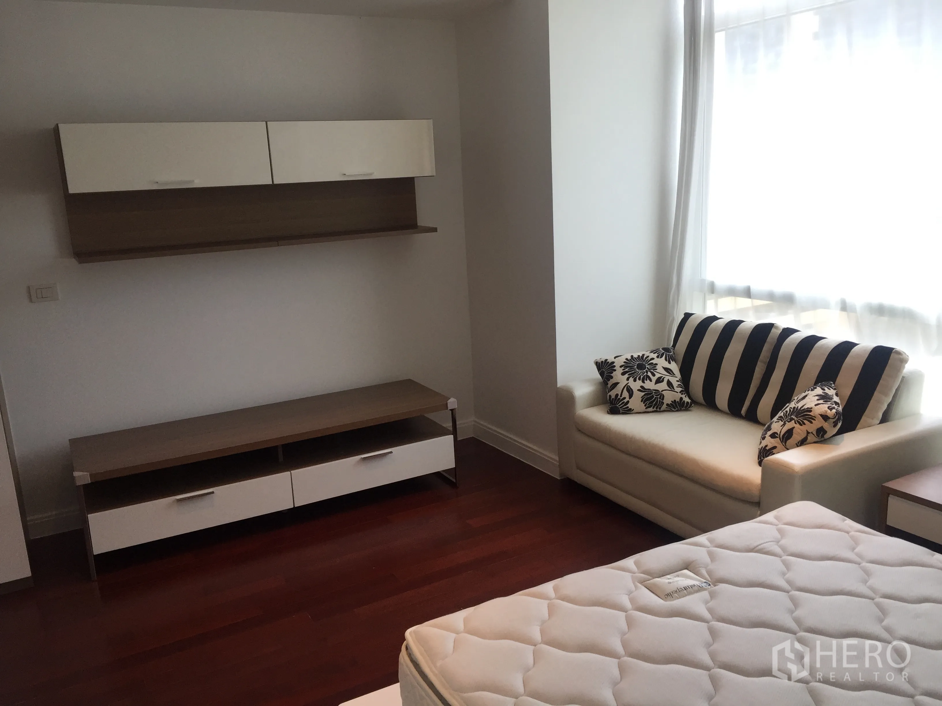 Condominium for rent in Pathum Wan, Bangkok - Cozy third bedroom with sofa, large window and wall-mounted storage cabinets.
