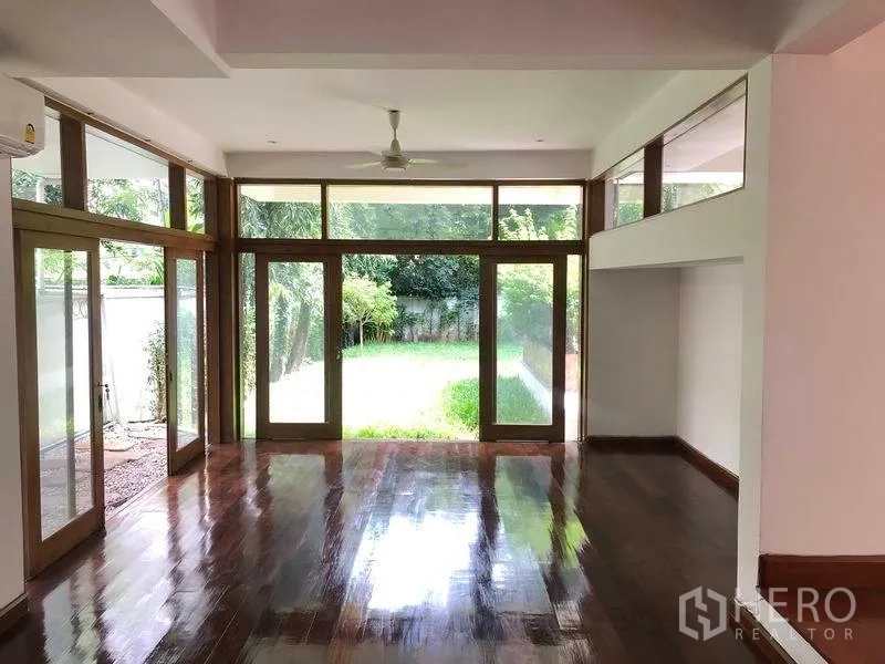 Detached House for rent in Watthana, Bangkok - Open living space with full-height windows facing a private lawn.