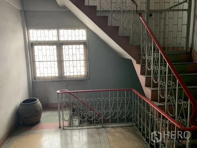 Shophouse for rent in Khlong Toei, Bangkok - Interior stairwell with vintage metal balustrade and window bringing natural light to the landings.