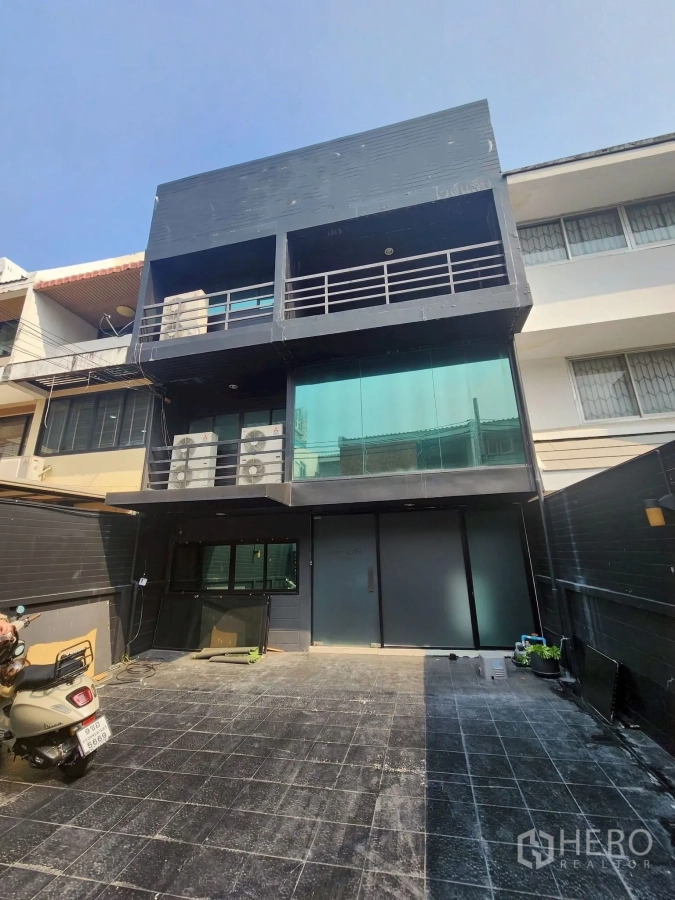 Home Office for rent in Khlong Toei, Bangkok - Three-story home office facade with dark cladding, glass frontage and private forecourt parking.