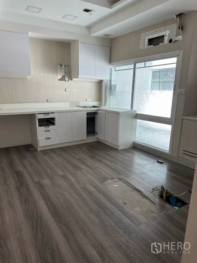 Shophouse for sale in Watthana, Bangkok - L-shaped pantry with sliding glass door and wood flooring, under light renovation.