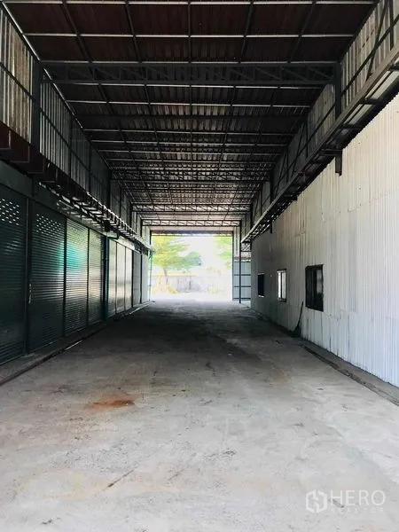 货栈 出租在Pathum Thani - 有顶穿行装卸通道，连接院场与内部库区，可见高挑屋架。