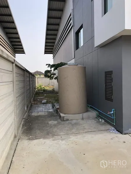 Warehouse for rent or sale in Lam Luk Ka, Pathum Thani - Utility area beside the building featuring a water tank and plumbing lines.