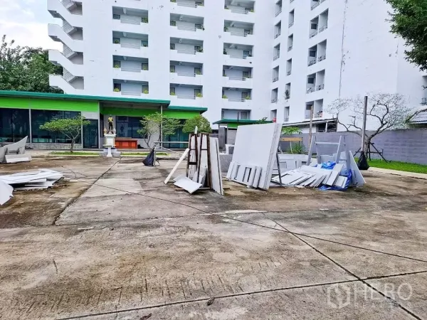 Warehouse for rent in Bang Kapi, Bangkok - Large open forecourt for loading and parking with landscaping and neighboring building in view.