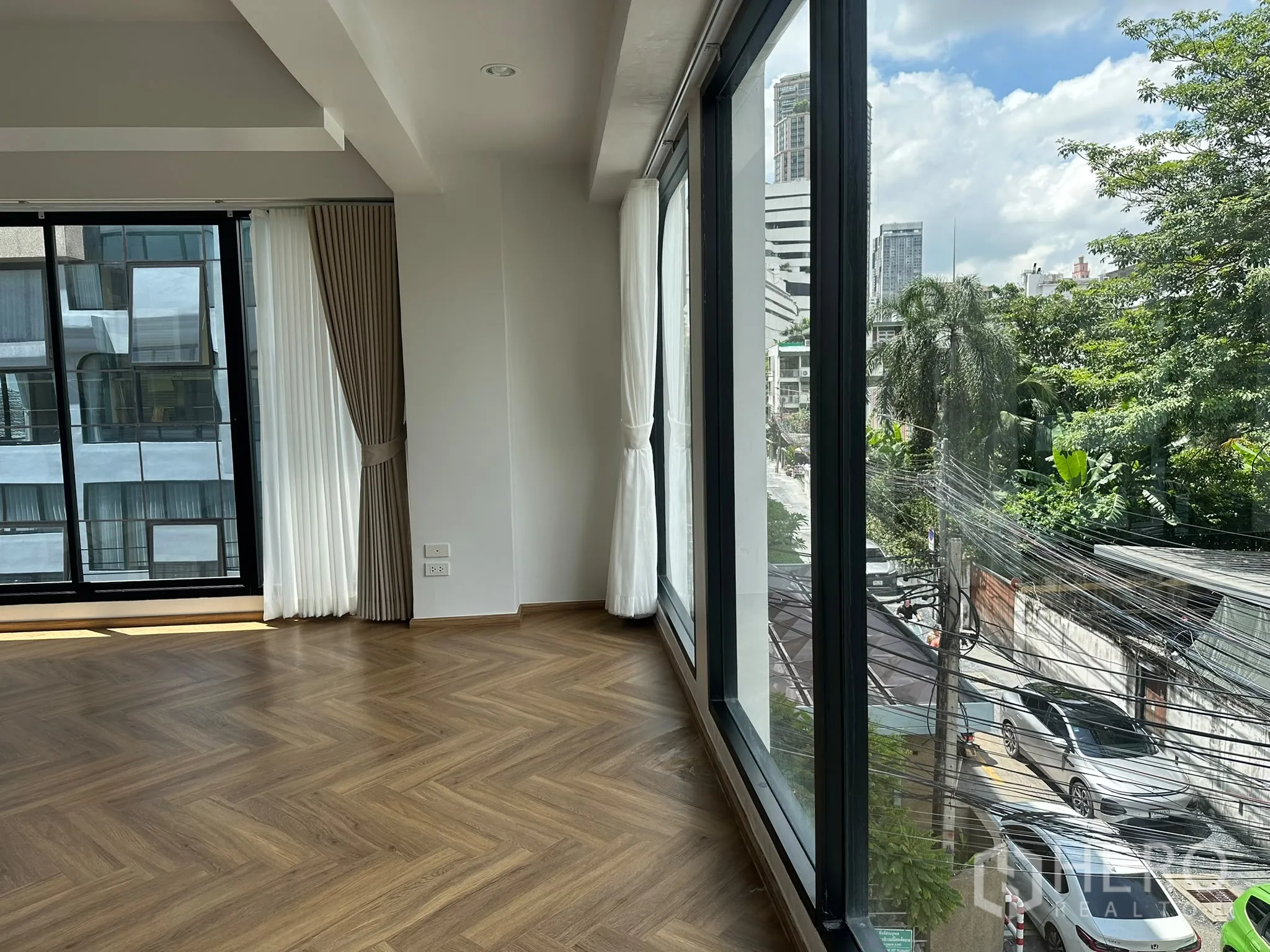 零售空间 for rent in Watthana, Bangkok - 转角零售空间配落地玻璃与薄纱窗帘，人字拼木地板，可见街景。