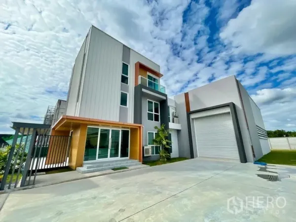 Warehouse for sale in Lam Luk Ka, Pathum Thani - Front view of a modern office building attached to a warehouse with wide driveway and parking apron.