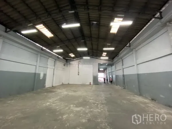 Warehouse for rent in Bang Phli, Samut Prakan - Empty warehouse aisle showing polished concrete floor, skylights and wide clear-span roof.