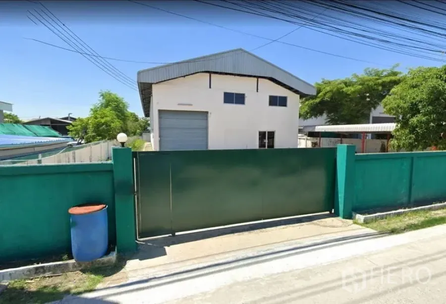 Factory for rent or sale in Bang Phli, Samut Prakan - Street-side view of the factory behind a secure green gate and perimeter wall.