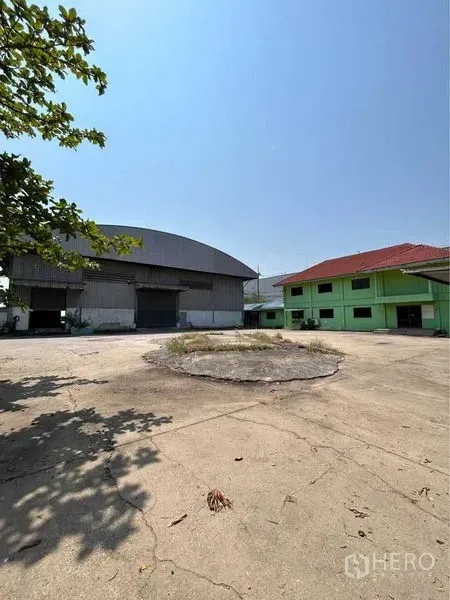 Warehouse for rent in Sam Phran, Nakhon Pathom - Wide concrete yard between the warehouse and green administrative building, ideal for truck maneuvering.