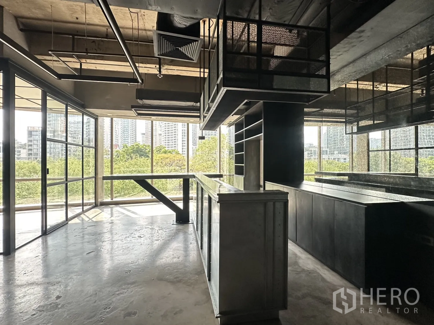 Office Space for rent in Pathum Wan, Bangkok - Open-plan workspace with long built-in counter, shelving, and panoramic windows over treetops and towers.