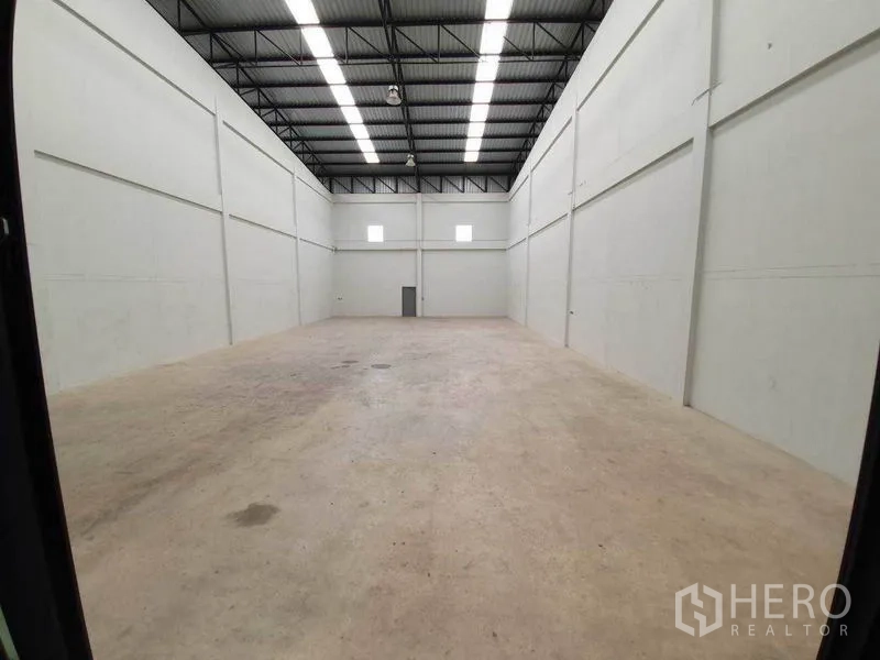 Factory for rent in Mueang Samut Sakhon, Samut Sakhon - Spacious high-ceiling warehouse bay with strip lighting, ventilation windows, and a durable concrete floor.