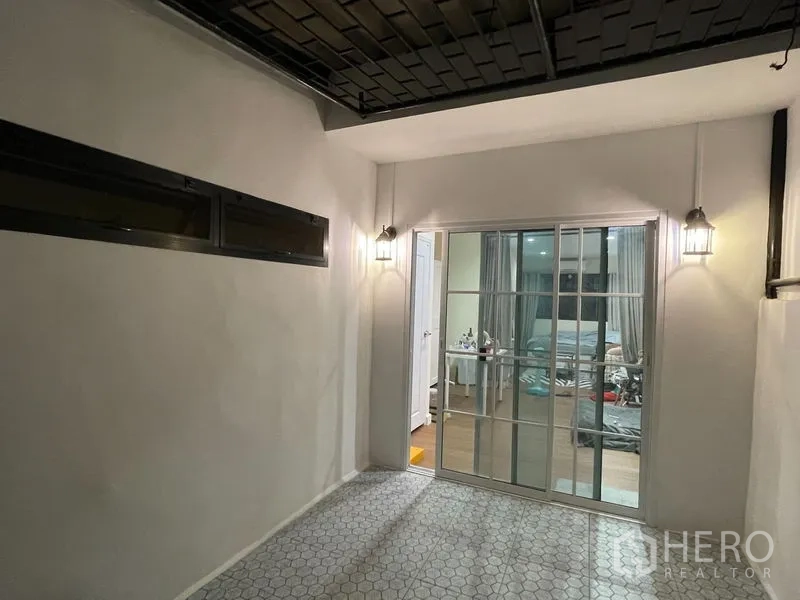 联排别墅 出租在Phra Khanong, Bangkok - 半室内露台，墙面壁灯与六角地砖，推拉门通房内。
