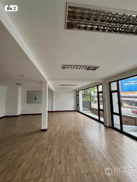 Shophouse for rent or sale in Khlong Toei, Bangkok - Second-floor showroom with floor-to-ceiling glass and tiled floors facing the road.