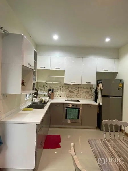 Townhouse for rent in Suan Luang, Bangkok - Full view of fitted kitchen with cooktop, oven, fridge and dining set.